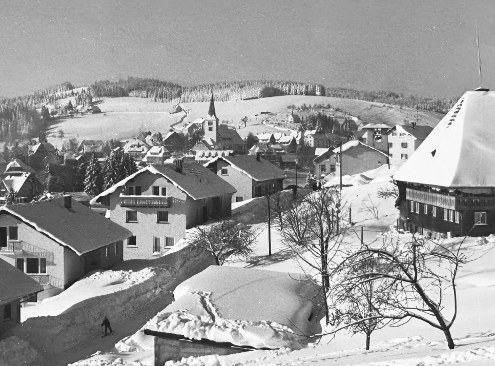 Höldbauernhof rechts am Rand mit Blick auf Dorf im Winter